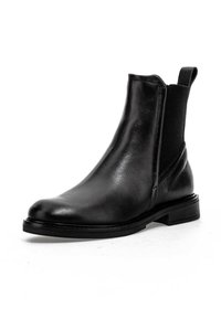 Bottine noire en cuir avec panneau latéral élastique et languette de tirage, talon bas et bout arrondi sur fond blanc.