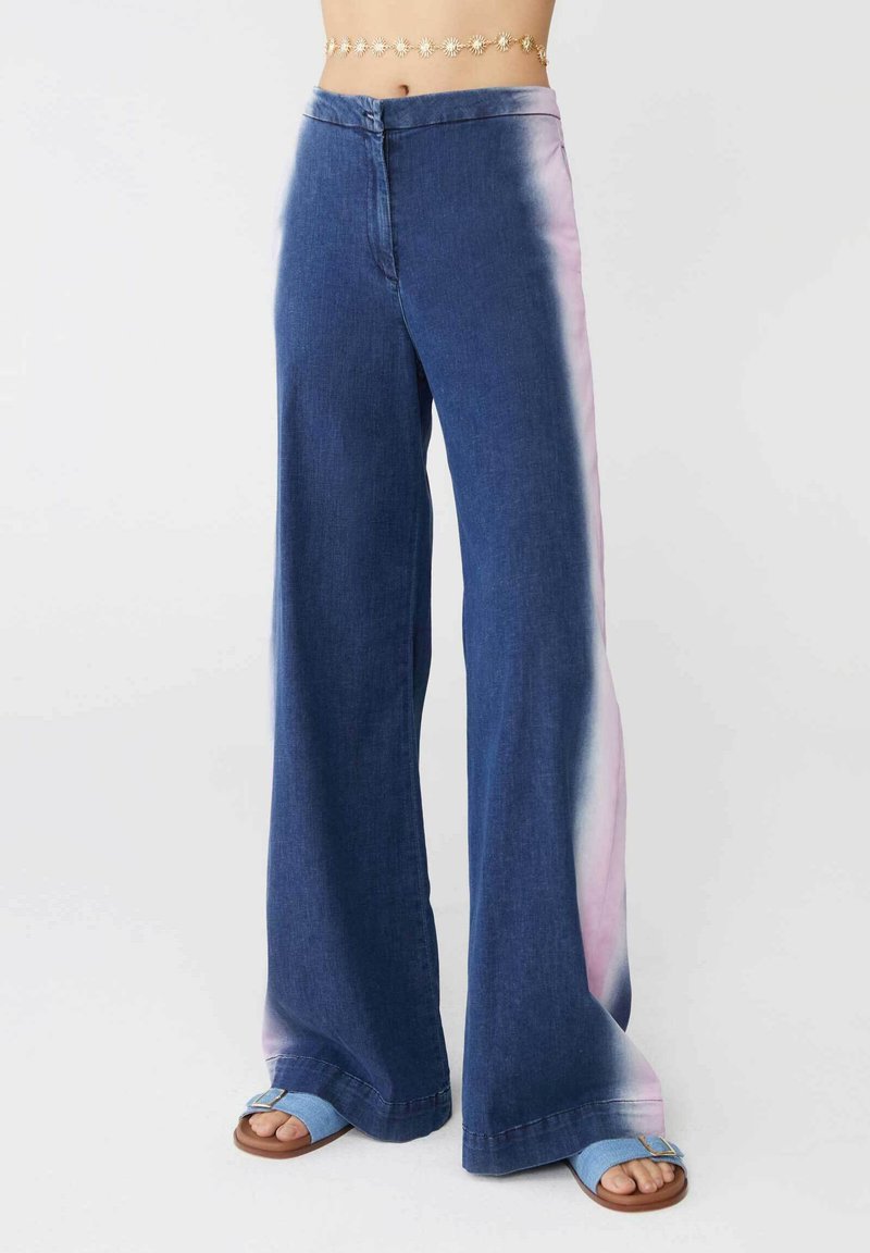 Pantaloni in denim a gamba larga con un lavaggio blu e un effetto ombre rosa lungo i lati. Realizzati in cotone con una texture liscia.