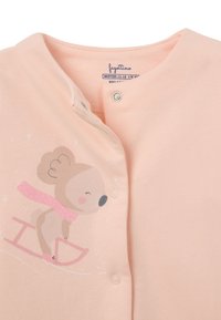 Hellrosa Bodysuit mit Rundhalsausschnitt, Druckknopfverschlüssen und einem Cartoon-Bären im Schlittschuhdesign. Weicher Stoff mit glatter Textur.