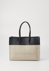 Borsa a tracolla con parte superiore in pelle nera texturizzata e parte inferiore in canvas beige, con il testo in rilievo "COCCINELLE" sul fronte e due manici.
