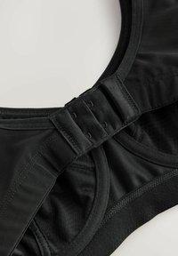 Zwarte sportbeha met meshpanelen, verstelbare haakjes, gladde naden en een elastische onderband voor ondersteuning. Zacht materiaal en afgeronde vorm.