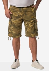 Kamuflage cargo shorts lavet af slidstærkt stof med flere lommer, en snøre i kanten, i nuancer af grøn og brun. Sammen med hvide sneakers.