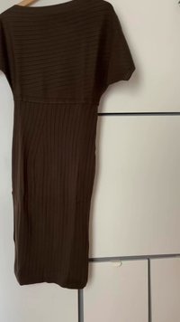 Robe marron côtelée à manches courtes, avec une silhouette ajustée et une texture lisse. Accrochée à un cintre en bois, avec un arrière-plan neutre.