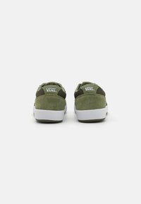 Adidași verzi din suede cu accente din plasă, tălpi de cauciuc alb, și marcaj Vans pe călcâi, prezentând un design low-top.