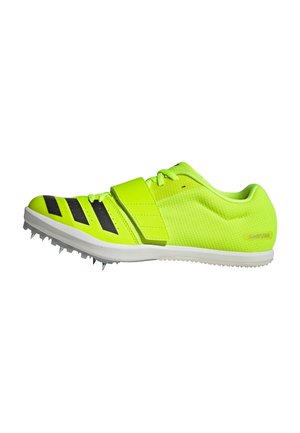 Neon yellow athletic shoe with black stripes, textured upper, and adjustable strap. Features sharp spikes on the sole for traction.