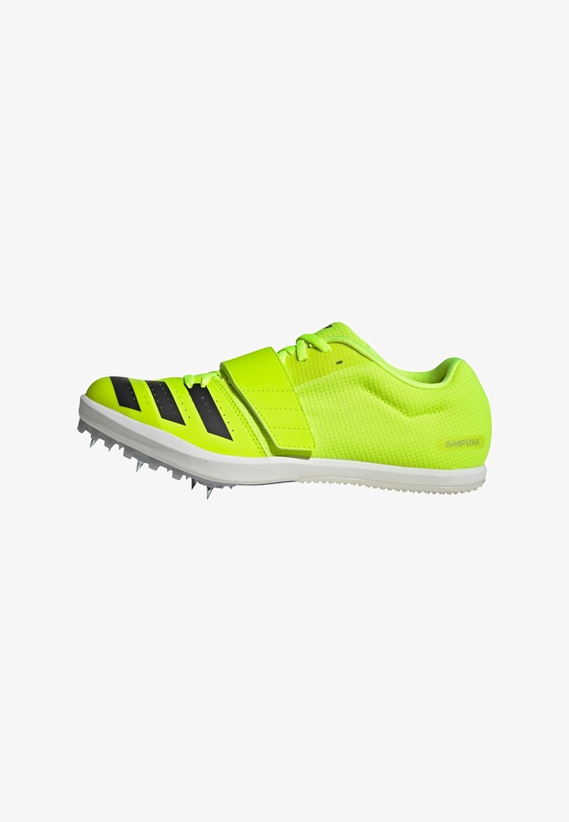 Scarpa sportiva gialla neon con strisce nere, parte superiore testurizzata e cinturino regolabile. Presenta punte affilate sulla suola per una migliore aderenza.