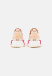 Rosa och beige träningsskor med en flexibel mesh-övre del, framträdande hälaccenter och en texturerad sula. Logotyp på baksidan.