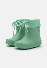 Bottes en caoutchouc imperméables vert menthe avec une semelle cannelée, un devant à lacets et un revers en caoutchouc doux et pliable, arborant un petit accent tricolore.