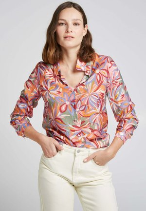 Chemise à boutons colorée avec un motif floral dans des nuances de rose, d'orange et de vert, fabriquée en tissu léger, avec un col et des manches retroussées.