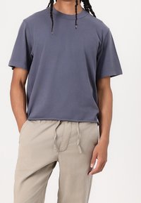 Donkerblauw katoenen T-shirt met korte mouwen, ronde hals en een comfortabele pasvorm, gecombineerd met lichtbeige broek met trekkoord.