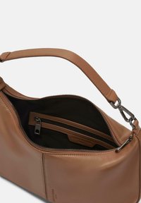 Borsa in pelle marrone chiaro con una texture liscia, manico corto, tasca interna con zip e fodera nera. Presenta un design minimalista e un branding sottile.