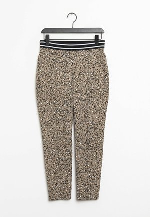 Mallas beige con estampado de leopardo en blanco y negro, con una cinturilla negra con rayas horizontales blancas, colgadas en una percha negra.