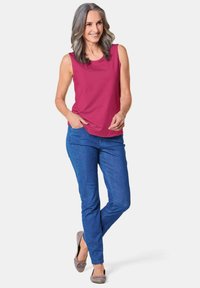 Mouwloze fuchsia blouse, blauwe spijkerbroek en grijze ballerina's. Glad stof, op maat gemaakte pasvorm en eenvoudige ronde halslijn. Geen patronen of extra accenten.