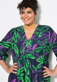Langärmliges Kleid aus navyfarbenem Stoff mit einem Blattmuster in Grün und Lila. Es hat einen V-Ausschnitt und einen elastischen Bund für eine betonte Silhouette.