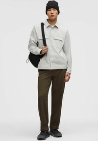 Hele hallikas pikkade varrukatega särk kahe eesmise taskuga, kombineeritud oliivroheliste pükstega ja mustade tossudega. Täiendatakse musta mütsi ja üle õla kantava kotiga.