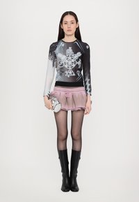 Long-sleeve top with black and gradient blue design featuring patterns; pink ruffled shorts; black knee-high boots; silver handbag.