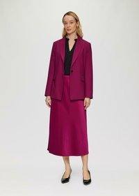 Magenta Blazer mit strukturierten Schultern und zwei vorderen Taschen, kombiniert mit einem passenden Midi-Rock. Beide aus glattem, leichtem Stoff gefertigt.