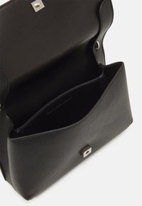 Černá kožená kabelka s texturovaným povrchem, opatřena zacvakávacím uzávěrem a otevřeným interiérem. Kompaktní obdélníkový tvar s minimalistickým designem.