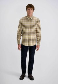 Geel en bruin geruite button-up shirt met lange mouwen, gecombineerd met donkere jeans en donkere schoenen. Gladde textuur en gestructureerd ontwerp.