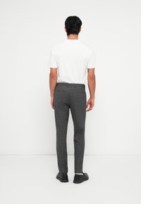 Grijs gerecheckerde broeken met een slim fit, gedragen met een plain wit T-shirt, voorzien van een textuur en zijzakken. Zwarte schoenen maken de look compleet.