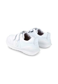 Zapatillas deportivas blancas con una parte superior sintética lisa, cordones elásticos, collar acolchado y suela de goma texturizada. Diseño minimalista.