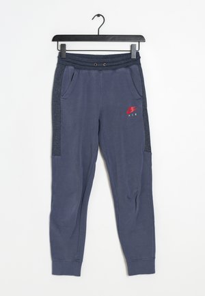 Navy jogger-housut, joissa on sivutaskut ja harmaat verkkokankaat, vasemmassa reidessä punainen Nike Air -logo ja joustava vyötärö.