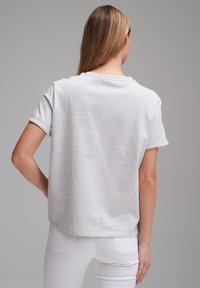 Grauer T-Shirt mit kurzen Ärmeln und umgeschlagenen Bündchen, lockere Passform, mit runder Ausschnitt und glatter Textur. Rückansicht dargestellt.