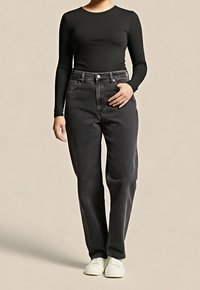 Top negro de manga larga combinado con jeans de talle alto y corte suelto en gris oscuro. Tejido texturizado con bolsillos delanteros y cierre de botones. Zapatos blancos.