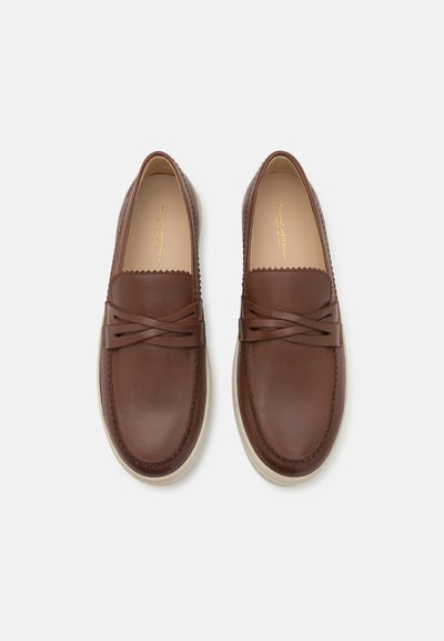 Chaussures en cuir marron à enfiler avec un bord festonné, ornées de brides croisées et d'une semelle en caoutchouc pour une meilleure adhérence. Texture lisse et design moderne.