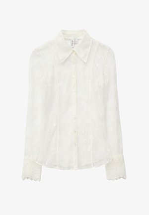 Weiße Spitzenbluse mit langen Ärmeln, Knopfleiste vorne und Kragen. Verziert mit zarten Blumenmustern und gezackten Spitzenmanschetten.