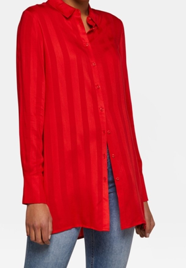 Camicia rossa a maniche lunghe con bottoni, caratterizzata da una fantasia a righe, con colletto e taglio dritto, abbinata a jeans blu.