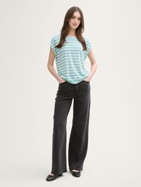 Tricou scurt cu mâneci scurte, ușor, în dungi, de culoare albastră, verde și gri; asortat cu blugi negri, cu talie înaltă, cu picioare largi și balerini negri.