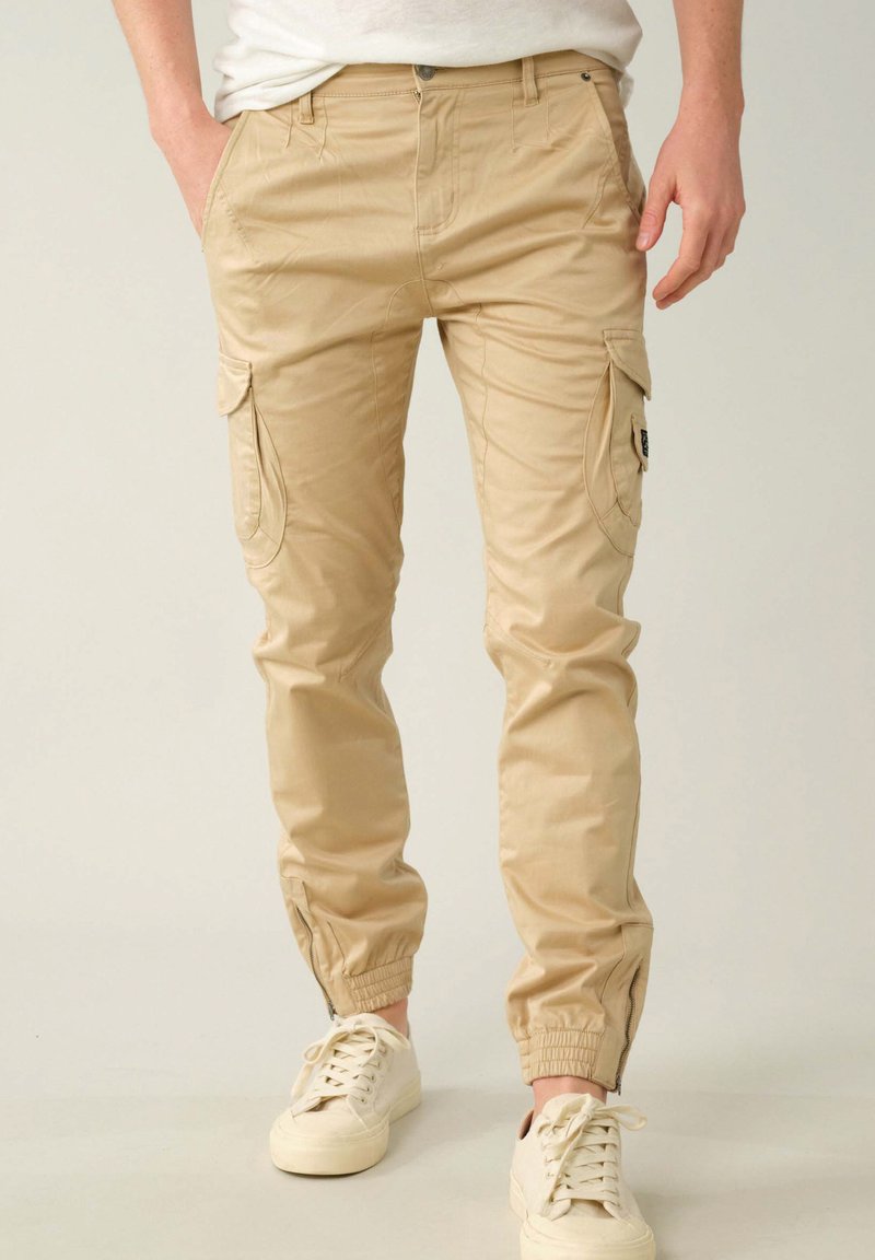 Khaki cargobroek van een katoenmix met zijzakken, elastische boorden en een voorste knoopsluiting. Fijne textuur, tapered fit, lichtgewicht ontwerp.