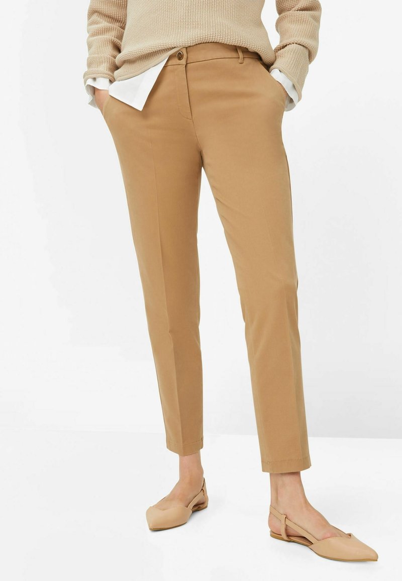 Tan chinos med slim fit, med knaplukning, forlommer og plissering. Sammen med lysebeige flade sko.