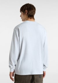 Long-sleeve gray t-shirt in a soft, textured fabric with a round neckline and relaxed fit, featuring a small brand tag at the hem.