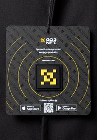 Czarny nylonowy znaczek z kwadratowym uchwytem na kod QR. Wyraźne żółte wzory i logo na teksturowanym tle z instrukcjami pobierania aplikacji.