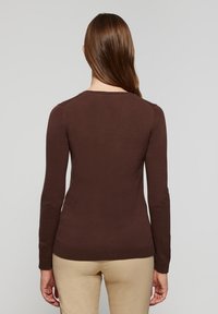 Pull marron à manches longues avec une coupe ajustée, des poignets côtelés et un col rond, confectionné en tissu tricoté doux. Aucun motif visible.