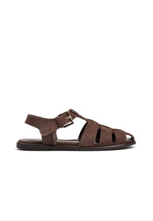 Brązowy zamszowy męski sandał rybacki z paskiem wokół kostki i złotą klamrą, płaską podeszwą i odkrytymi palcami.