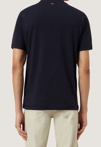 Mörkblå polo-shirt med klassisk krage, korta ärmar och en subtil logodetalj nära halsringningen. Tillverkad av mjukt bomullstyg.