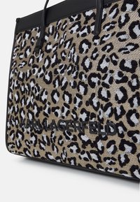 Kabelka z látky s leopardím potiskem a černými koženými akcenty, s pevným tvarem a embosovaným logem na přední straně. Texturovaný povrch.