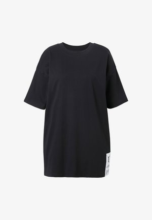 Schwarzes, übergroßes T-Shirt mit kurzen Ärmeln und Rundhalsausschnitt, mit einem weißen Patch-Label nahe dem unteren Saum auf der linken Seite.