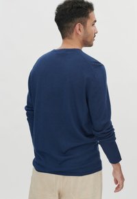 Dunkelblaues Langarmshirt mit Rundhalsausschnitt, gerippten Bündchen und figurbetontem Schnitt, gefertigt aus weichem, strukturiertem Stoff.