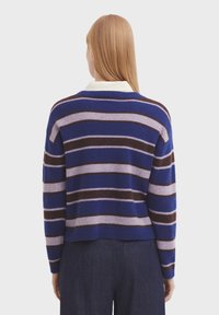 Striped sweater in blue, purple, and brown. Soft texture with a rounded neckline and dropped shoulder design. Hemline slightly cropped.