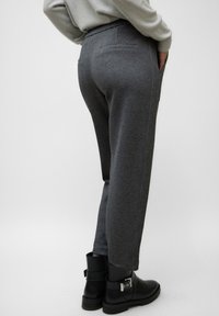 Pantalones de punto grises con un corte holgado, con cintura elástica, bolsillos laterales y piernas estrechas, combinados con botines negros.