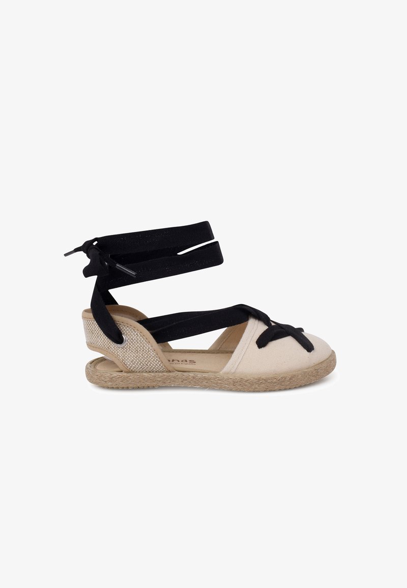 Sandalo espadrille con suola in juta intrecciata, parte superiore in tela beige e doppi cinturini neri in tessuto per il supporto della caviglia con dettaglio a fiocco.