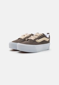Pair of dark gray suede sneakers with cream wave detail, cream laces, and thick white rubber soles on white background.