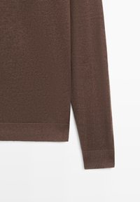 Pull en maille marron à manches longues, vue de la manche et du côté sur fond blanc, montrant les poignets et l'ourlet côtelés.