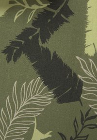 Tessuto verde con un motivo a foglie in nero e crema chiaro, caratterizzato da forme e texture variabili, adatto per rivestimenti o moda.