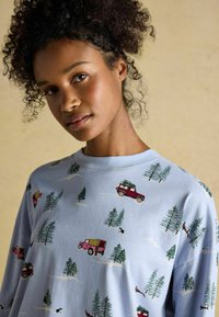 Svetlomodrá bavlnená mikina so vzorom starožitných nákladných áut, stromov a divokej zveri. Dizajn s okrúhlym výstrihom a voľným strihom.