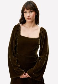 Robe en velours vert foncé avec un col carré, des manches longues froncées et un corsage ajusté, révélant une texture douce et un design élégant.